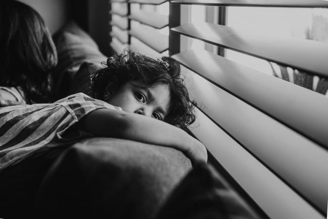 black and white image of little girl over the couch with in-home Perth lifestyle newborn photographer