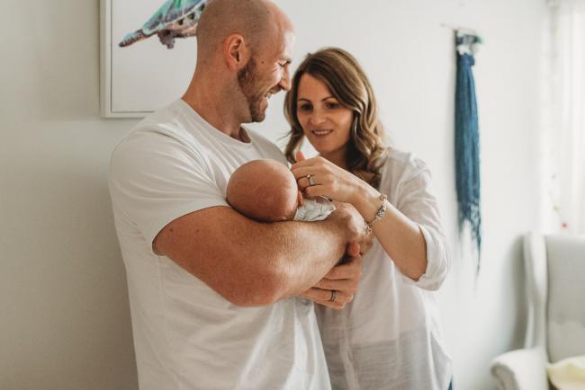 Father holding baby and smiling at mother with Perth Newborn photographer Alana Prosper Photography