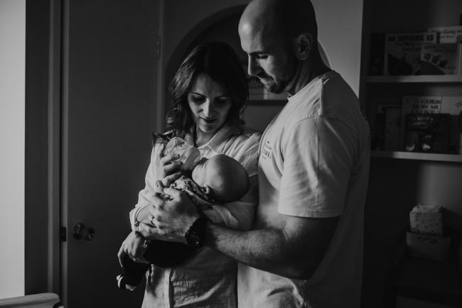 Black and white image of mother bottle feeding baby with father next to them with Perth Newborn photographer Alana Prosper Photography