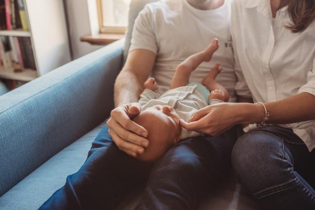 Baby laying across father's lap as mother touches his face with Perth Newborn photographer Alana Prosper Photography