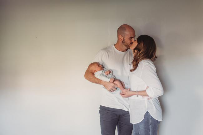 Parents holding baby and kissing with Perth Newborn photographer Alana Prosper Photography
