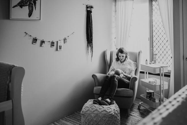 black and white image of mother on chair in nursery with Perth newborn lifestyle photographer Alana Prosper Photography