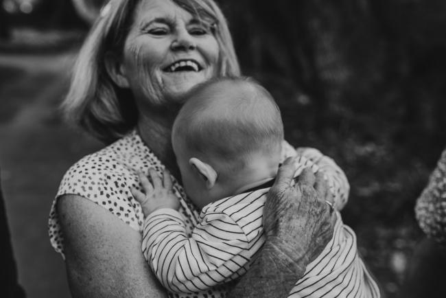 black and white image of grandmother holding baby during extended family session at Hyde Park with Perth family photographer Alana Prosper Photography