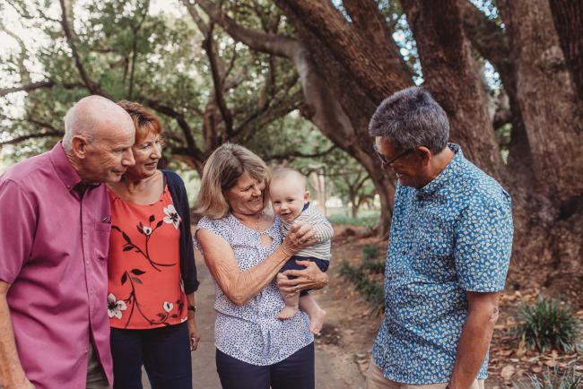 Baby smiling as being held by grandparents during extended family session at Hyde Park with Perth family photographer Alana Prosper Photography