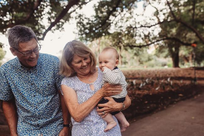 Grandparents smiling as holding baby during extended family session at Hyde Park with Perth family photographer Alana Prosper Photography