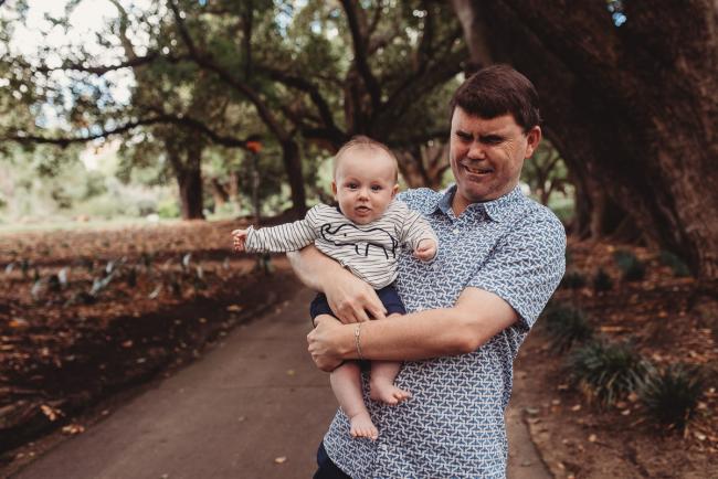 Baby being held by uncle during extended family session at Hyde Park with Perth family photographer Alana Prosper Photography