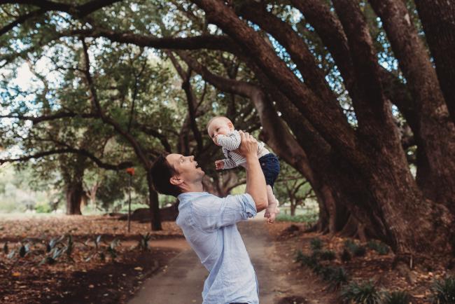 Father lifting baby in the air during extended family session at Hyde Park with Perth family photographer Alana Prosper Photography