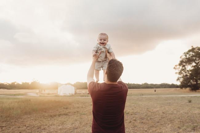 Father lifting baby in the air who is smiling with Perth Family Photographer Alana Prosper Photography at Perry's Paddock