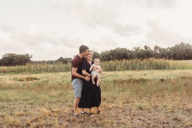 Father kissing mother as she holds baby with Perth Family Photographer Alana Prosper Photography at Perry's Paddock