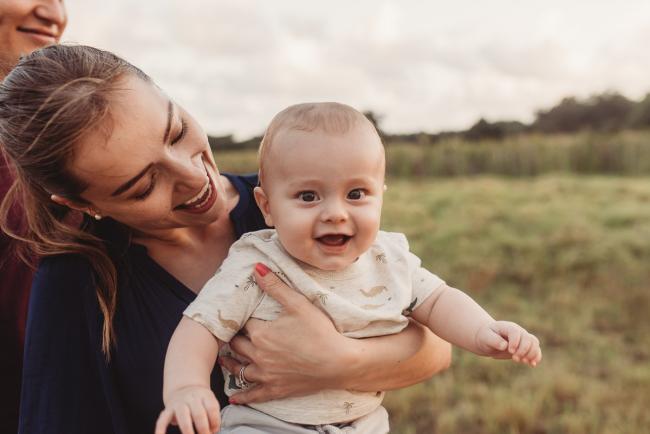 Baby smiling as being held by mother with Perth Family Photographer Alana Prosper Photography at Perry's Paddock