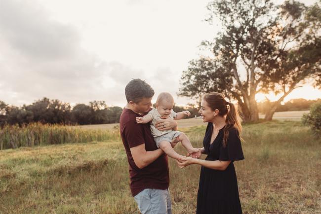 Father holding baby as mother touches his feet with Perth Family Photographer Alana Prosper Photography at Perry's Paddock