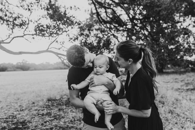 black and white image of parents kissing baby with Perth Family Photographer Alana Prosper Photography at Perry's Paddock