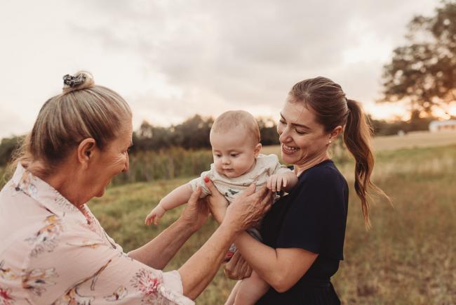 Mother holding baby as grandmother reaches for him with Perth Family Photographer Alana Prosper Photography at Perry's Paddock