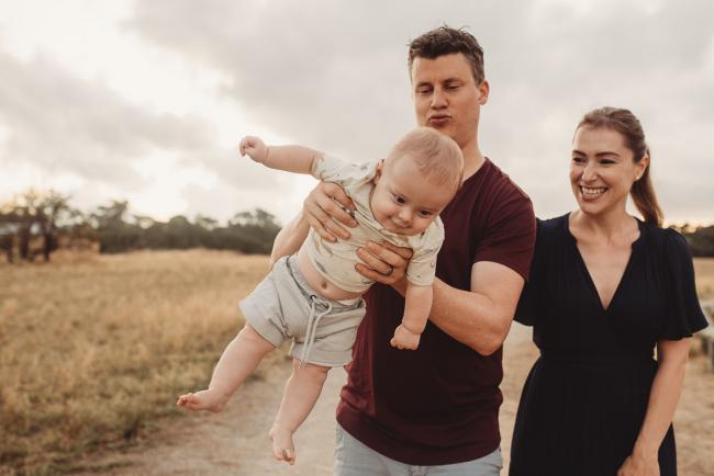 Father flying baby as mother smiles with Perth Family Photographer Alana Prosper Photography at Perry's Paddock