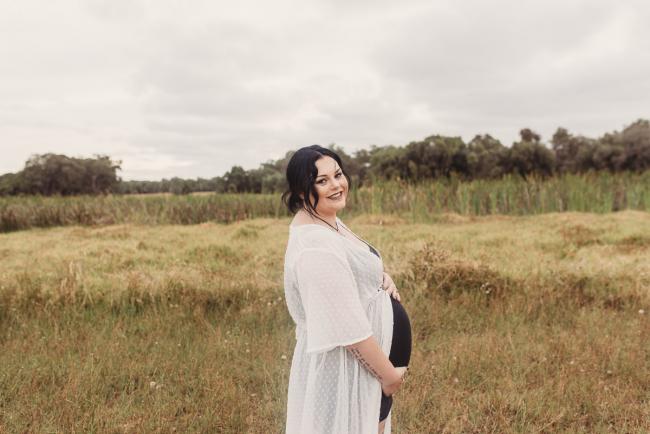 Pregnant woman smiling at the camera with Perth maternity photographer at Perry's Paddock