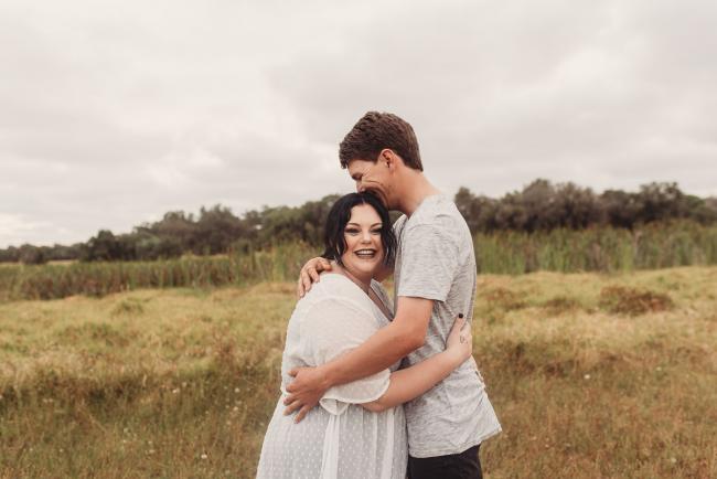 Pregnant couple hugging with Perth maternity photographer at Perry's Paddock