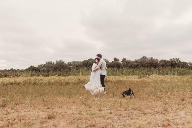 Pregnant couple hugging with Perth maternity photographer at Perry's Paddock