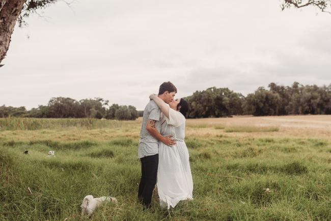 Pregnant couple kissing with Perth maternity photographer at Perry's Paddock
