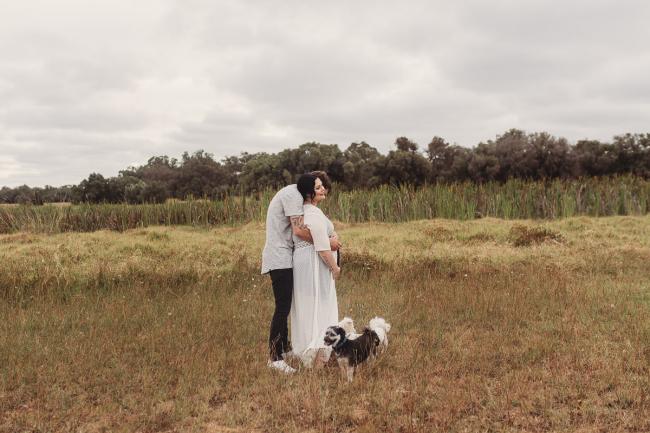 Man hugging his pregnant partner with dogs at their feet with Perth maternity photographer at Perry's Paddock