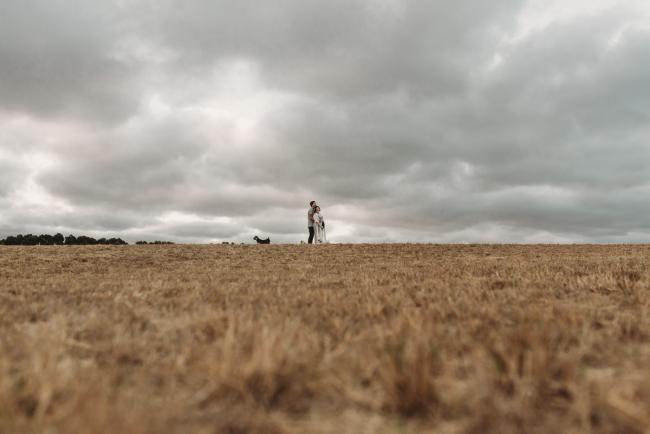 Pregnant couple hugging with dogs at their feet with Perth maternity photographer at Perry's Paddock