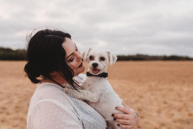 Pregnant woman holding white dog with Perth maternity photographer at Perry's Paddock