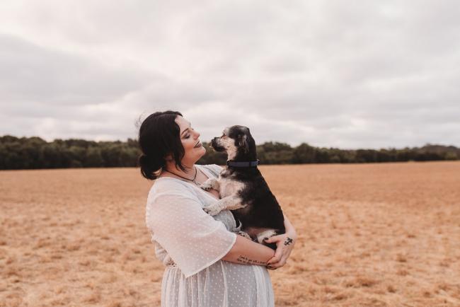 Pregnant woman holding black dog with Perth maternity photographer at Perry's Paddock