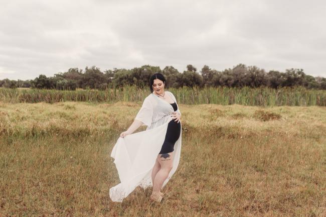 Pregnant woman holding her dress out with Perth maternity photographer at Perry's Paddock