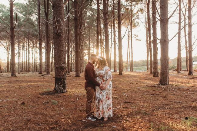 Couple holding hands and looking at each other at The Pines with Perth maternity photographer Alana Prosper Photography