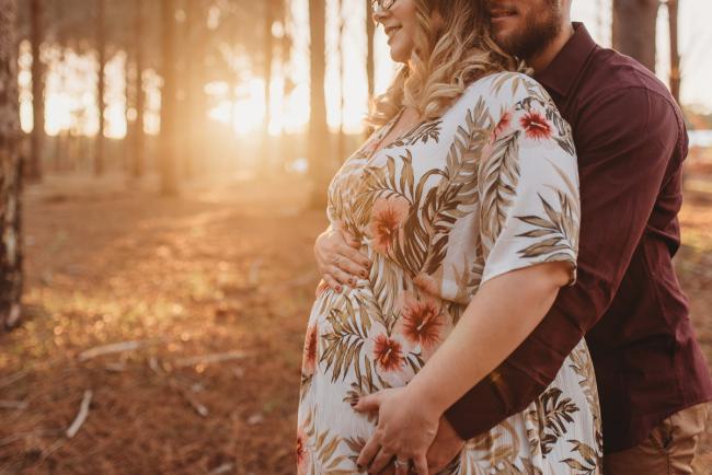 Man hugging woman from behind at The Pines with Perth maternity photographer Alana Prosper Photography