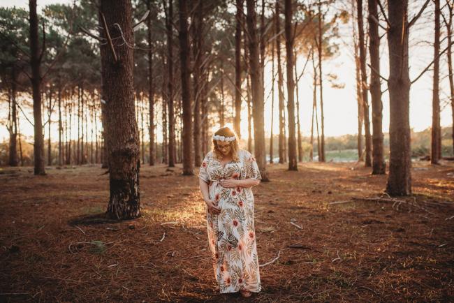 Pregnant woman looking down at her tummy at The Pines with Perth maternity photographer Alana Prosper Photography