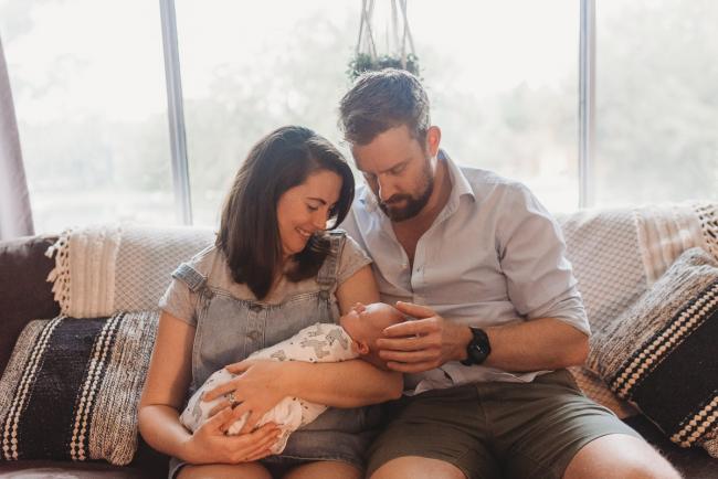parents holding newborn baby on couch with Perth newborn photographer Alana Prosper Photography