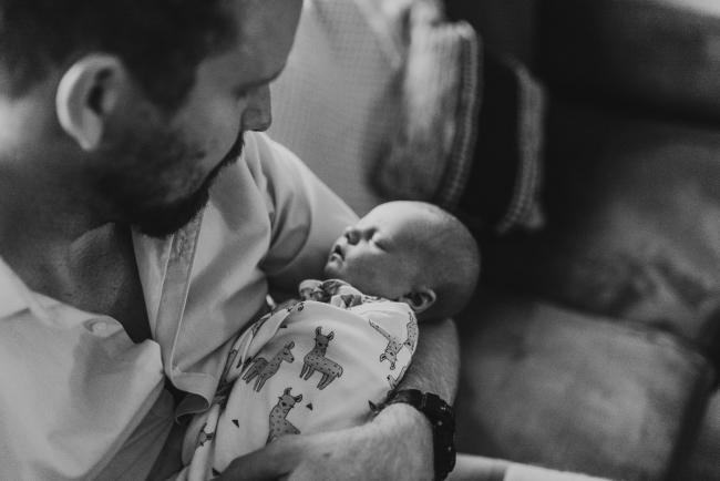 black and white image of newborn in father's arms with Perth newborn lifestyle photographer Alana Prosper Photography