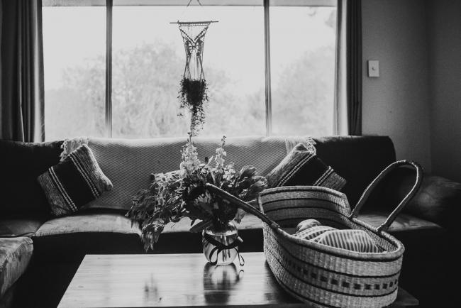 black and white image of baby in bassinet on coffee table with Perth newborn lifestyle photographer Alana Prosper Photography