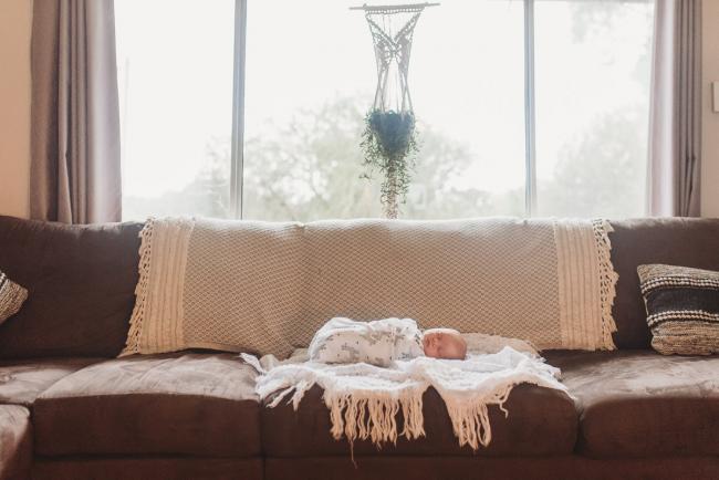 newborn baby in wrap on couch with Perth newborn lifestyle photographer Alana Prosper Photography