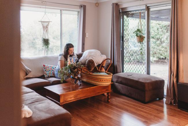 mother looking at baby in bassinet on coffee table with Perth newborn lifestyle photographer Alana Prosper Photography