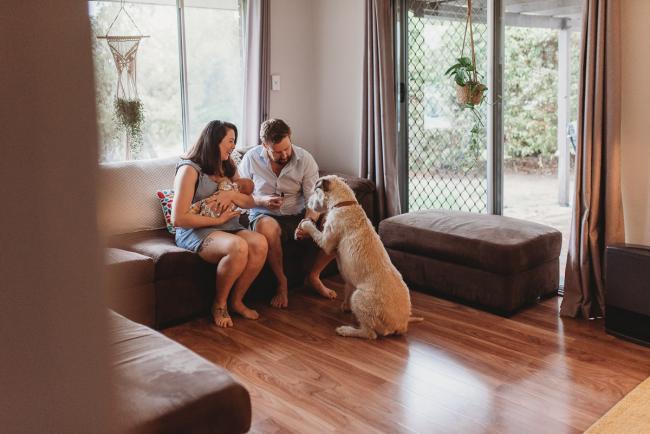 Parents and dog on couch with newborn baby with Perth newborn lifestyle photographer Alana Prosper Photography