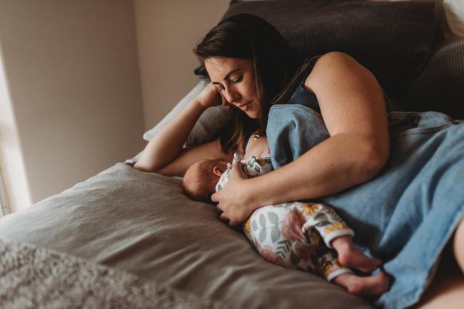 mother feeding on bed with Perth newborn photographer Alana Prosper Photography