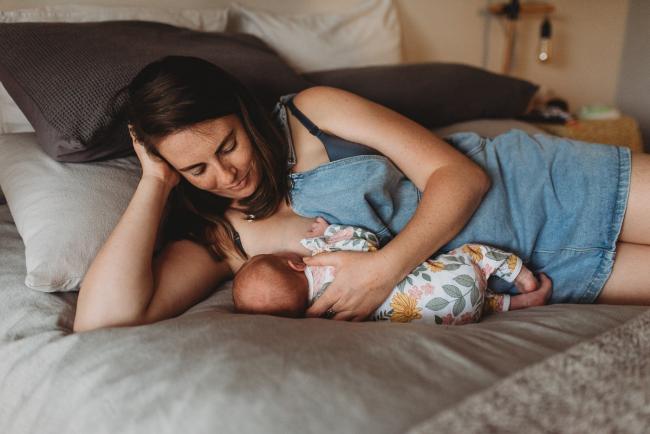 mother laying on bed and feeding baby with Perth newborn lifestyle photographer Alana Prosper Photography