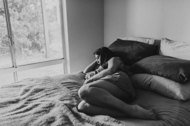 black and white image of mother laying on bed feeding baby with Perth newborn lifestyle photographer Alana Prosper Photography
