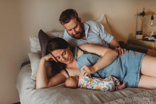 Parents laying on bed with baby with Perth newborn lifestyle photographer Alana Prosper Photography