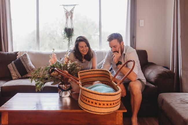 parents looking at baby in bassinet on coffee table with Perth newborn lifestyle photographer Alana Prosper Photography