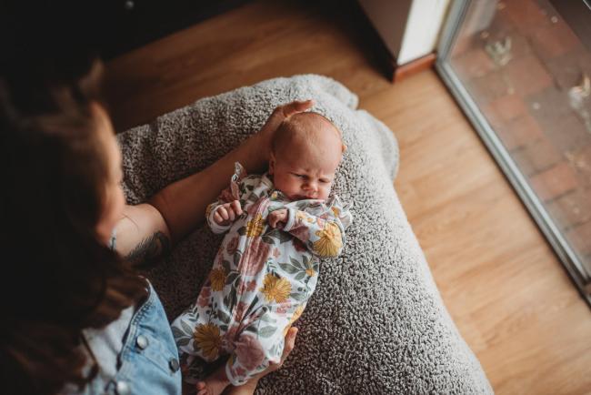 Baby on bed next to mother with Perth newborn lifestyle photographer Alana Prosper Photography