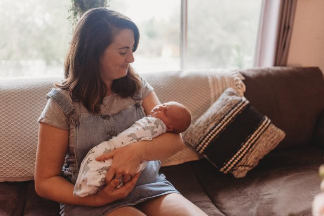 mother holding new baby on couch with Perth newborn photographer Alana Prosper Photography