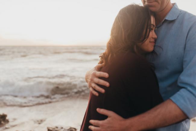 man hugging woman as she leans against him with Perth Family Photographer Alana Prosper Photography at Burns Beach