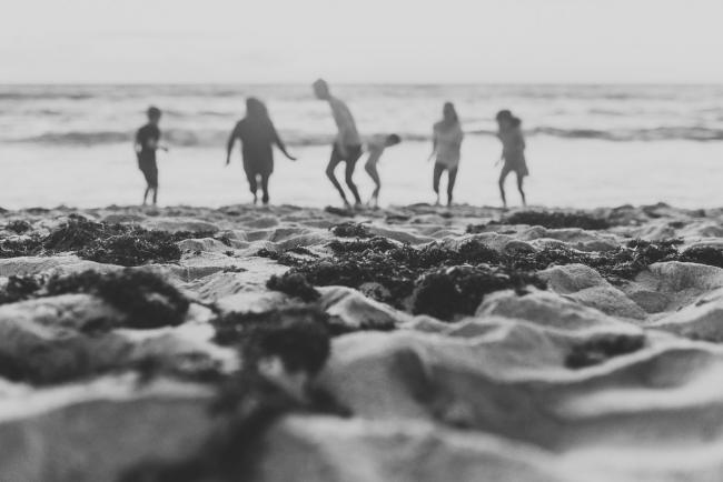 black and white image of family running at the beach with Perth family photographer Alana Prosper Photography at Burns Beach