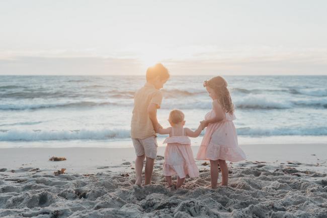 three kids holding hands on the beach with family photographer Perth at Burns Beach, Alana Prosper Photography