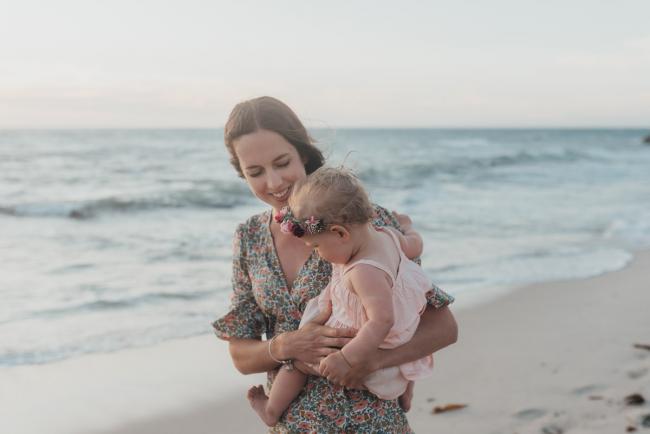 mother holding baby girl on the beach with family photographer Perth at Burns Beach, Alana Prosper Photography