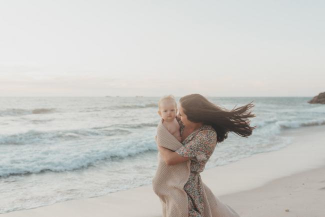 mother holding baby girl with blanket on the beach with family photographer Perth at Burns Beach, Alana Prosper Photography