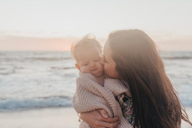 mother kissing baby girl on the beach with family photographer Perth at Burns Beach, Alana Prosper Photography