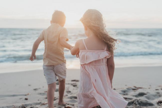 brother holding his sisters hand on the beach with family photographer Perth at Burns Beach, Alana Prosper Photography